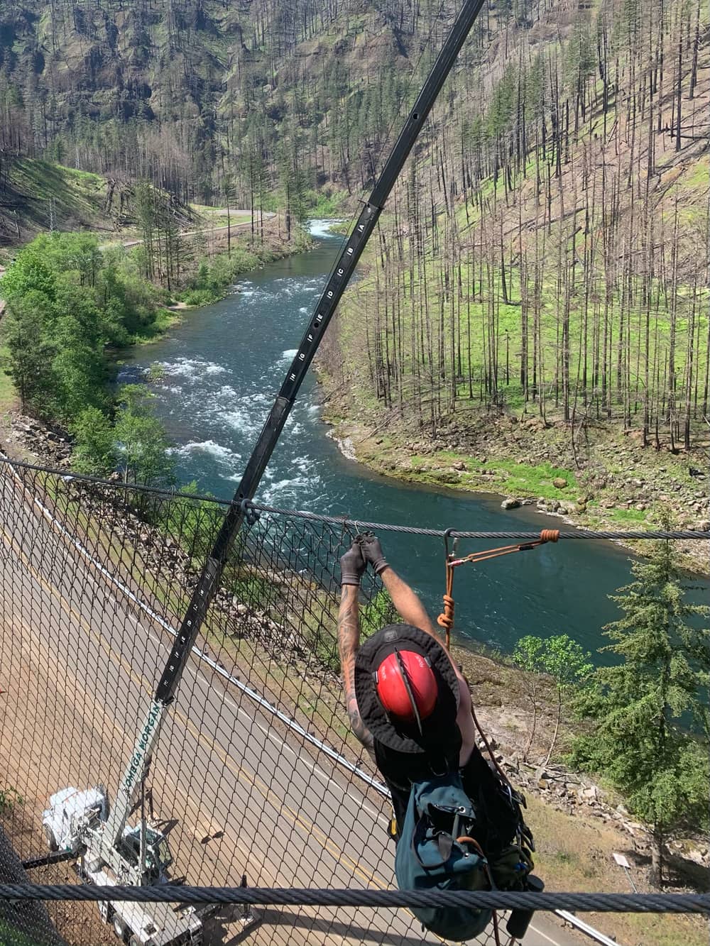 A photo of a professionally trained worker installing attenuator mesh on a hillside