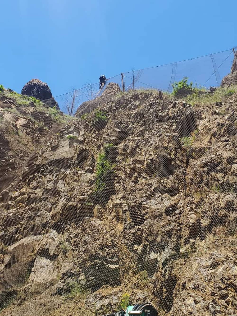 attenuator mesh being installed on hillside