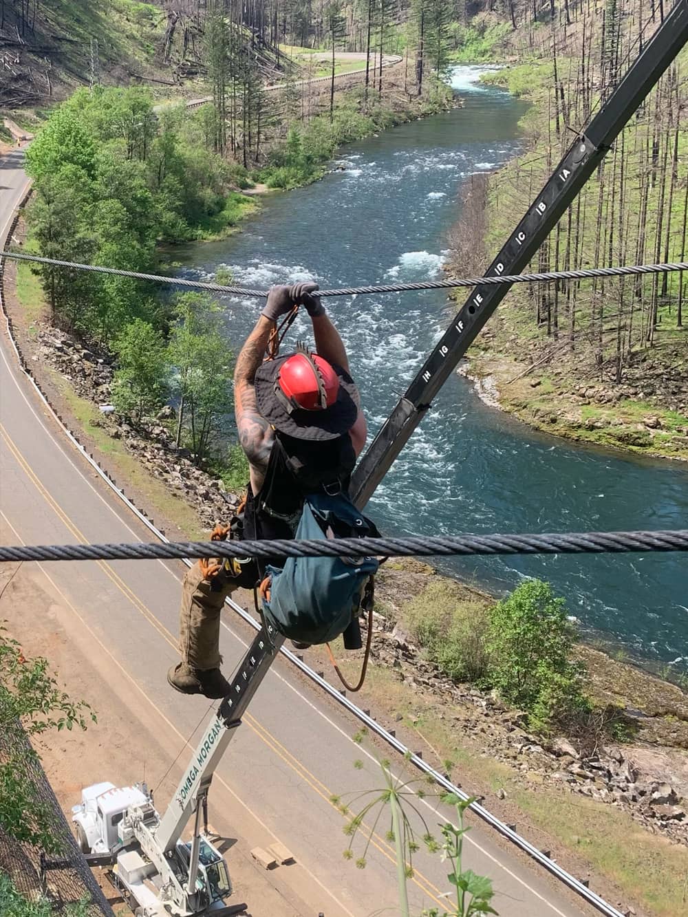 A photo of a professionally trained worker installing attenuator mesh on a hillside