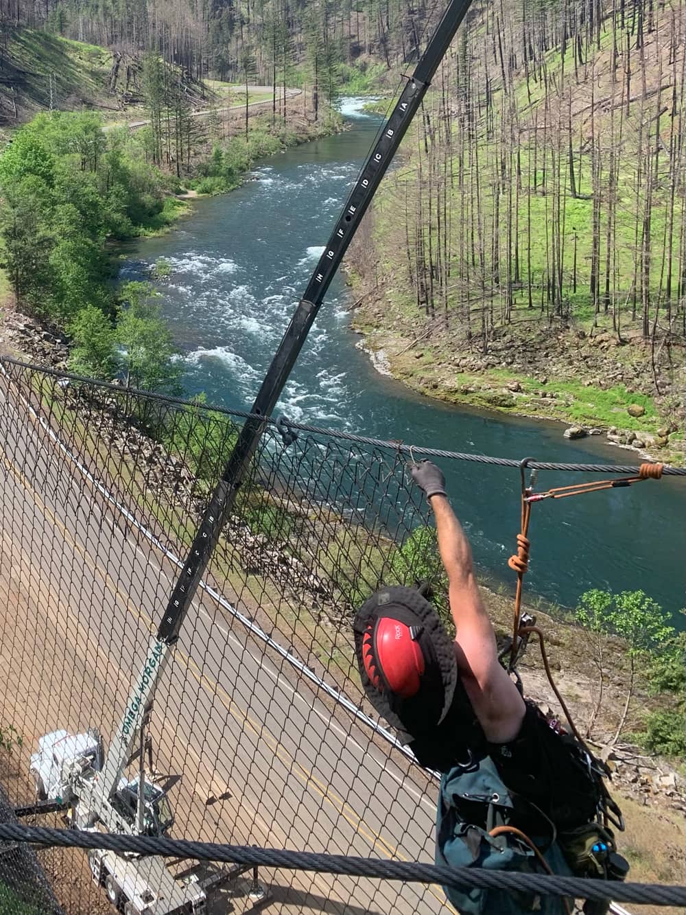 A photo of a professionally trained worker installing attenuator mesh on a hillside