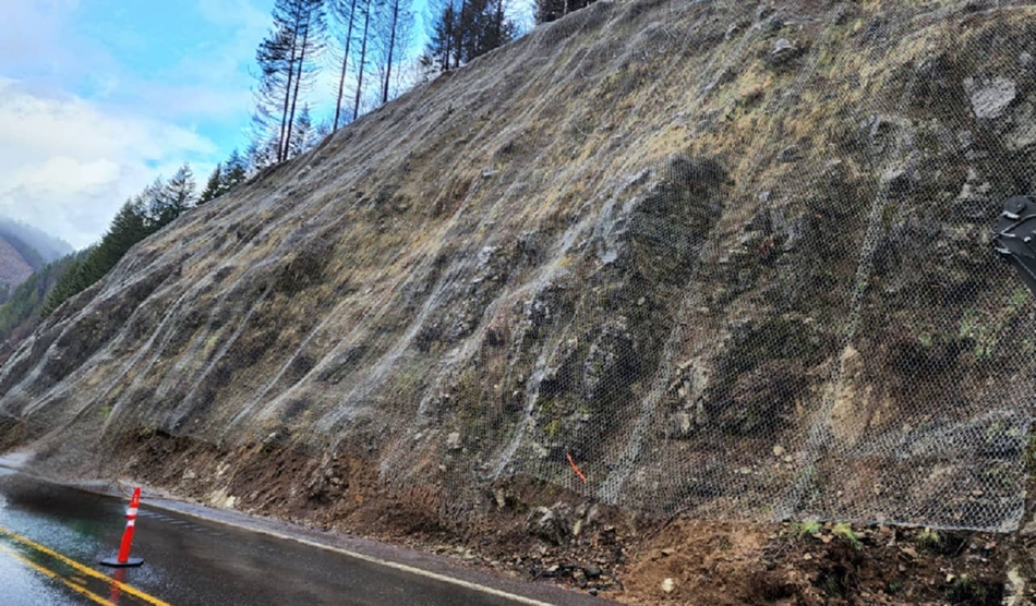 A photo of a highway road cut draped in mesh to prevent rock slides