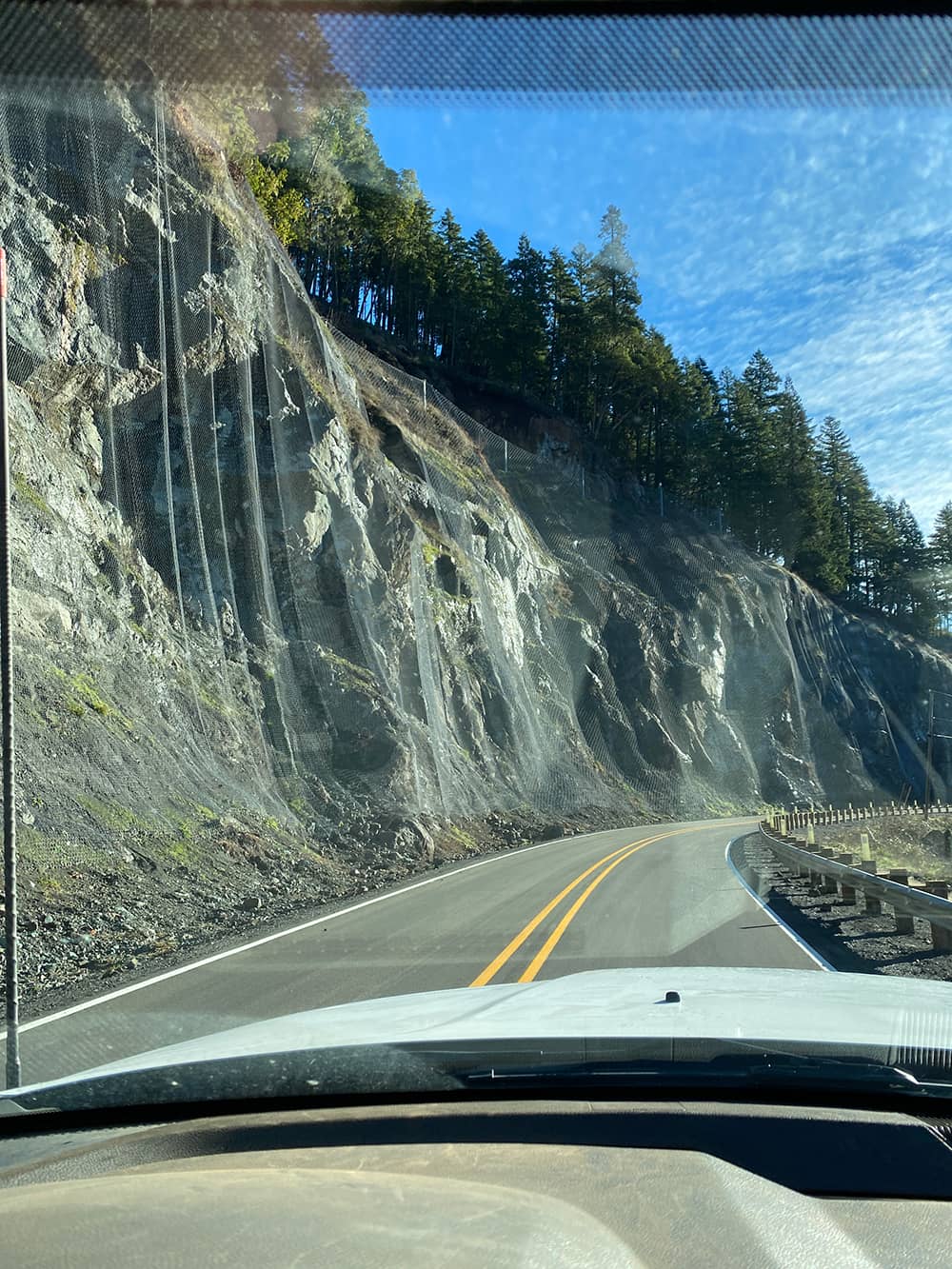 A photo of installed draped mesh over a road cut along a highway