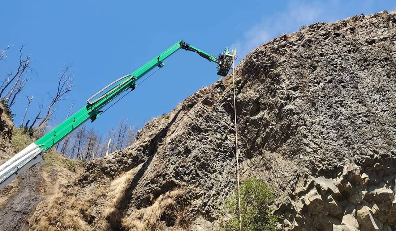 A photo of trained professionals using a crane to perform remote access rock and soil drilling