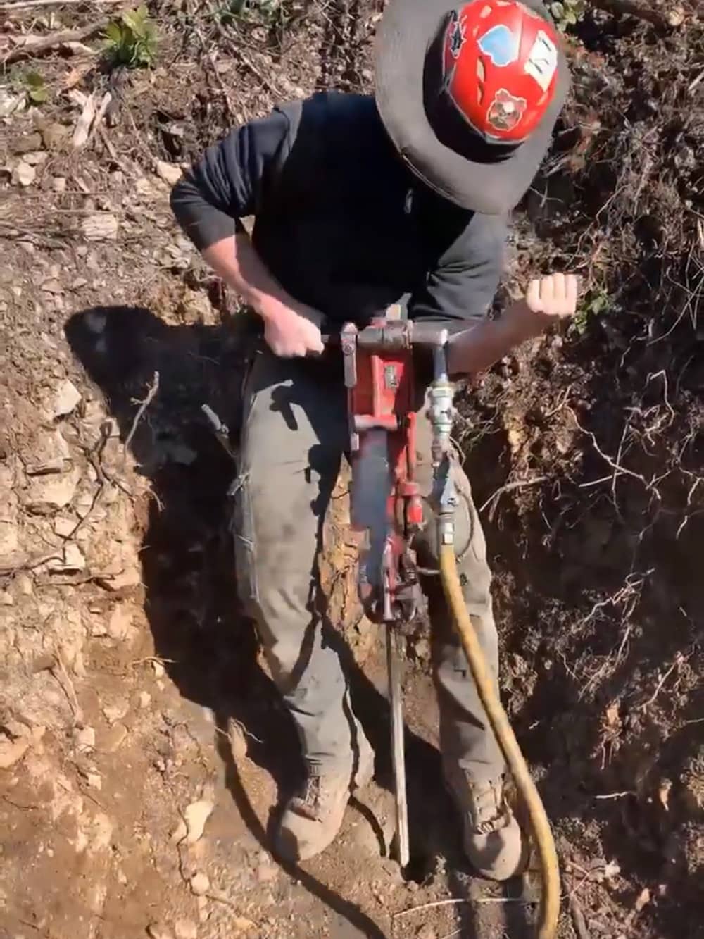 A photo of a trained working using a drill on a remote access project