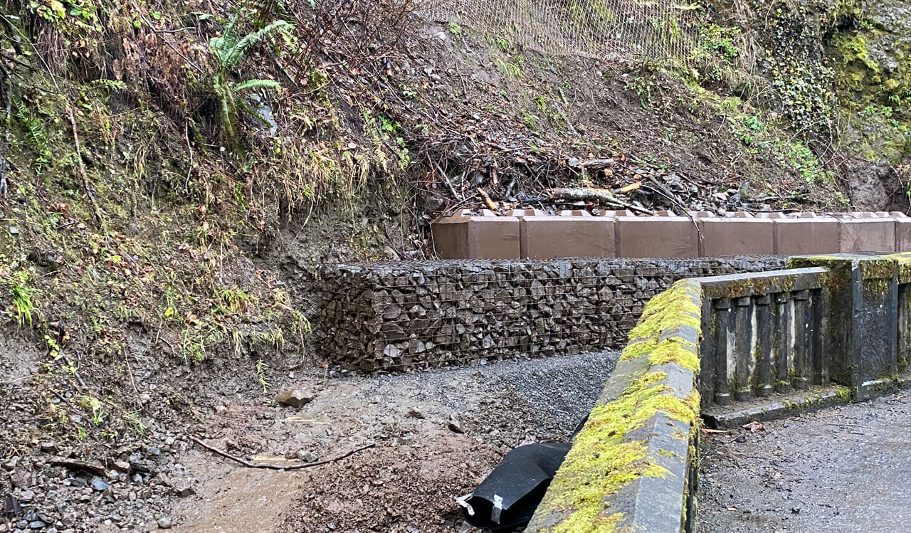 A photo of a mesh and rock protective barrier along a highway