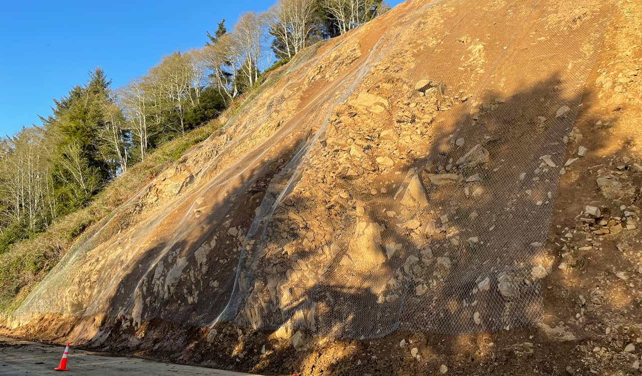 A photo of draped mesh over a rock cut along a highway